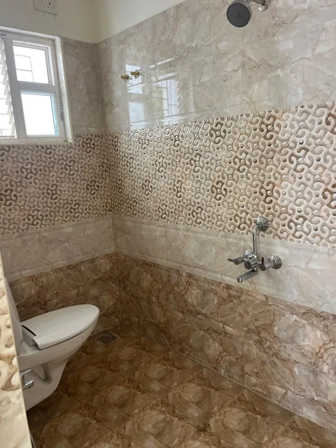 A bedroom bathroom with patterned wall tiles and shower fittings